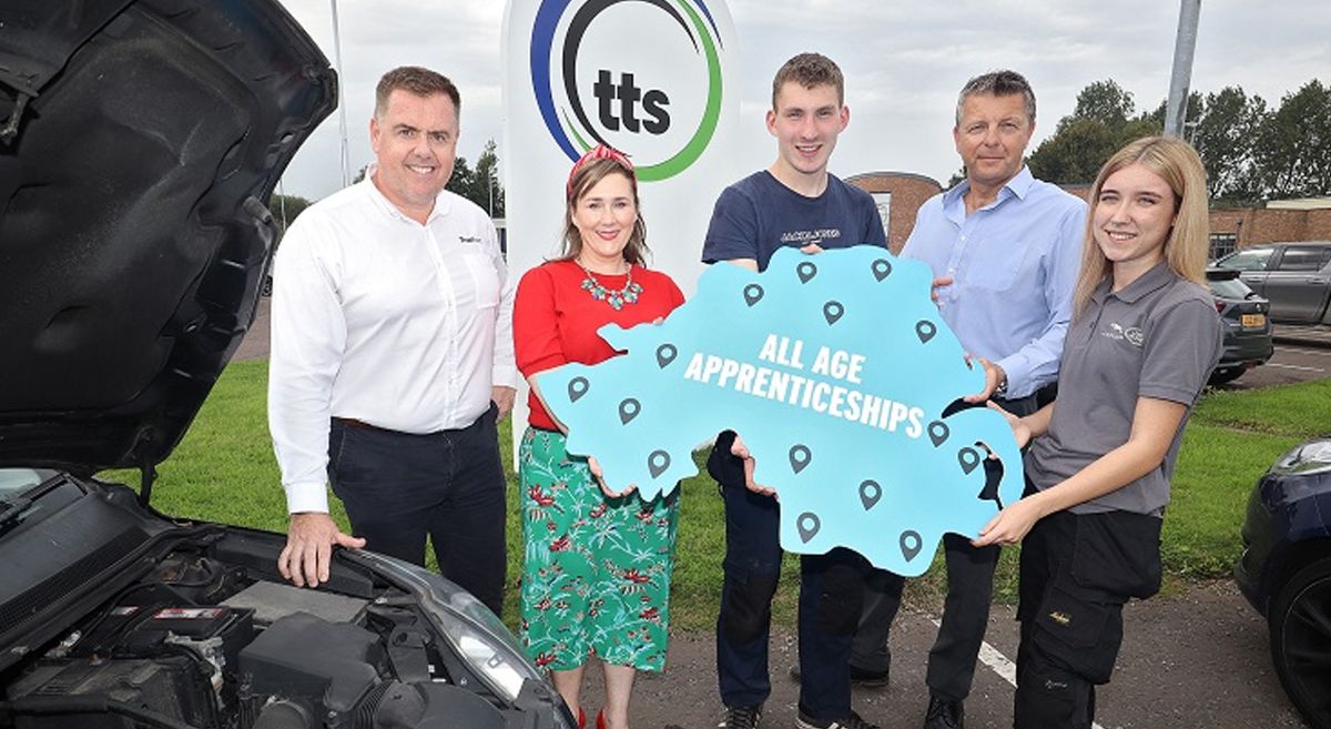 Five people holding a  cut out map of Northern Ireland lined up beside the open bonnet of a vehicle